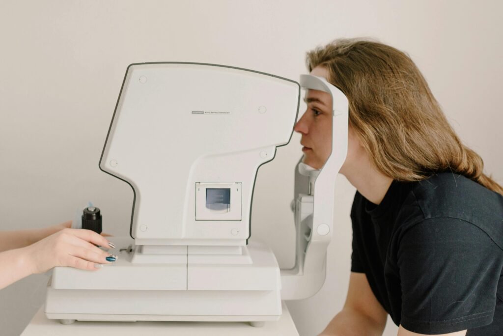 Side view of crop anonymous doctor checking eyesight of female patient using vision screening device in clinic